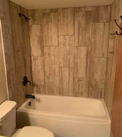 The same tub alcove after: a new tub with a wood-look tile surround and dark-finish fixtures.