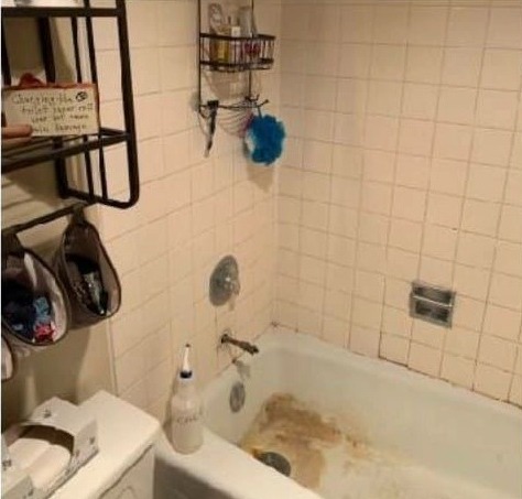 Bathroom tub alcove before the remodel: a stained tub and dated white wall tile.