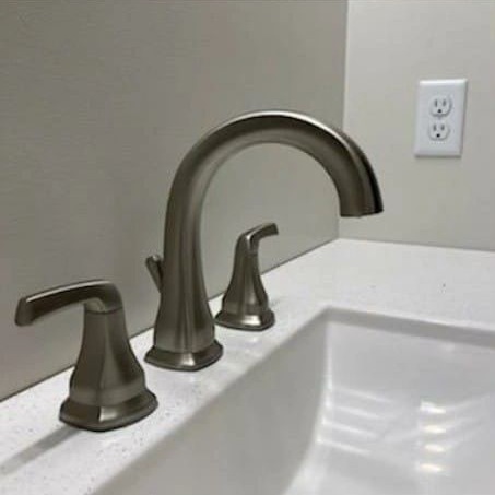 A brushed two-handle basin tap on a white countertop.